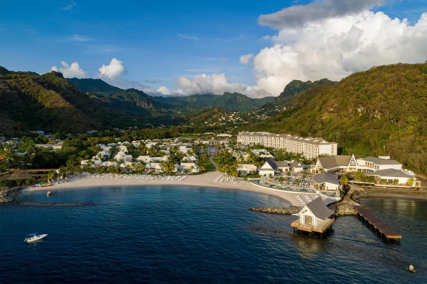Aerial beachfront view of Sandals St. Vincent and the Grenadines with mountains behind the resort.