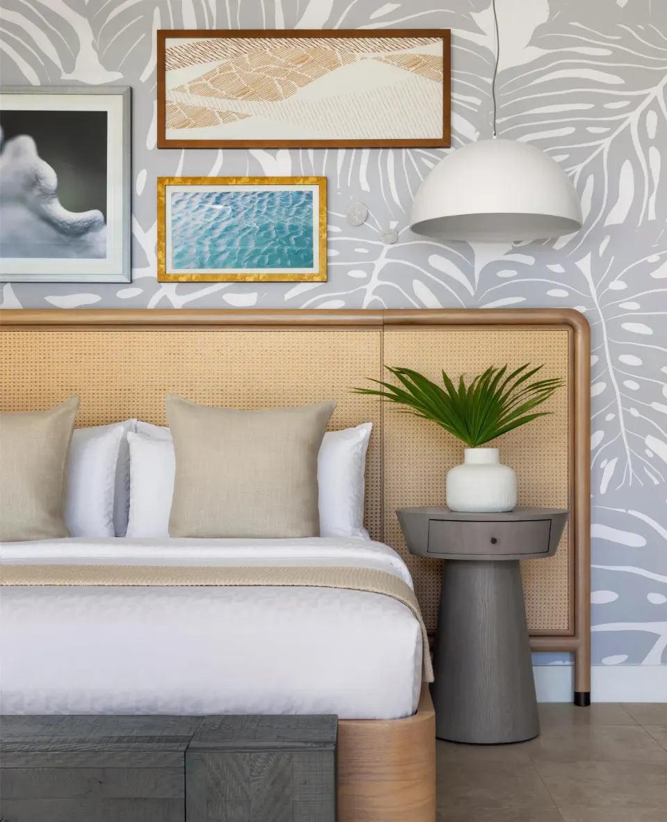 King bed with cane headboard and tropical wall art at Sandals St. Vincent and the Grenadines.