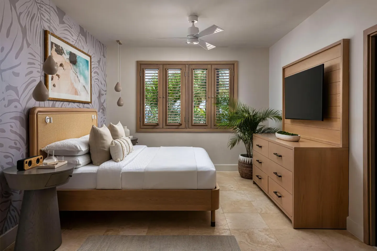 Guest room with king bed, wood shutters, and wall-mounted TV at Sandals St. Vincent and the Grenadines.