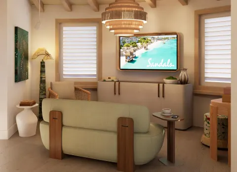 Guest room sitting area with sofa and TV at Sandals St. Vincent and the Grenadines.