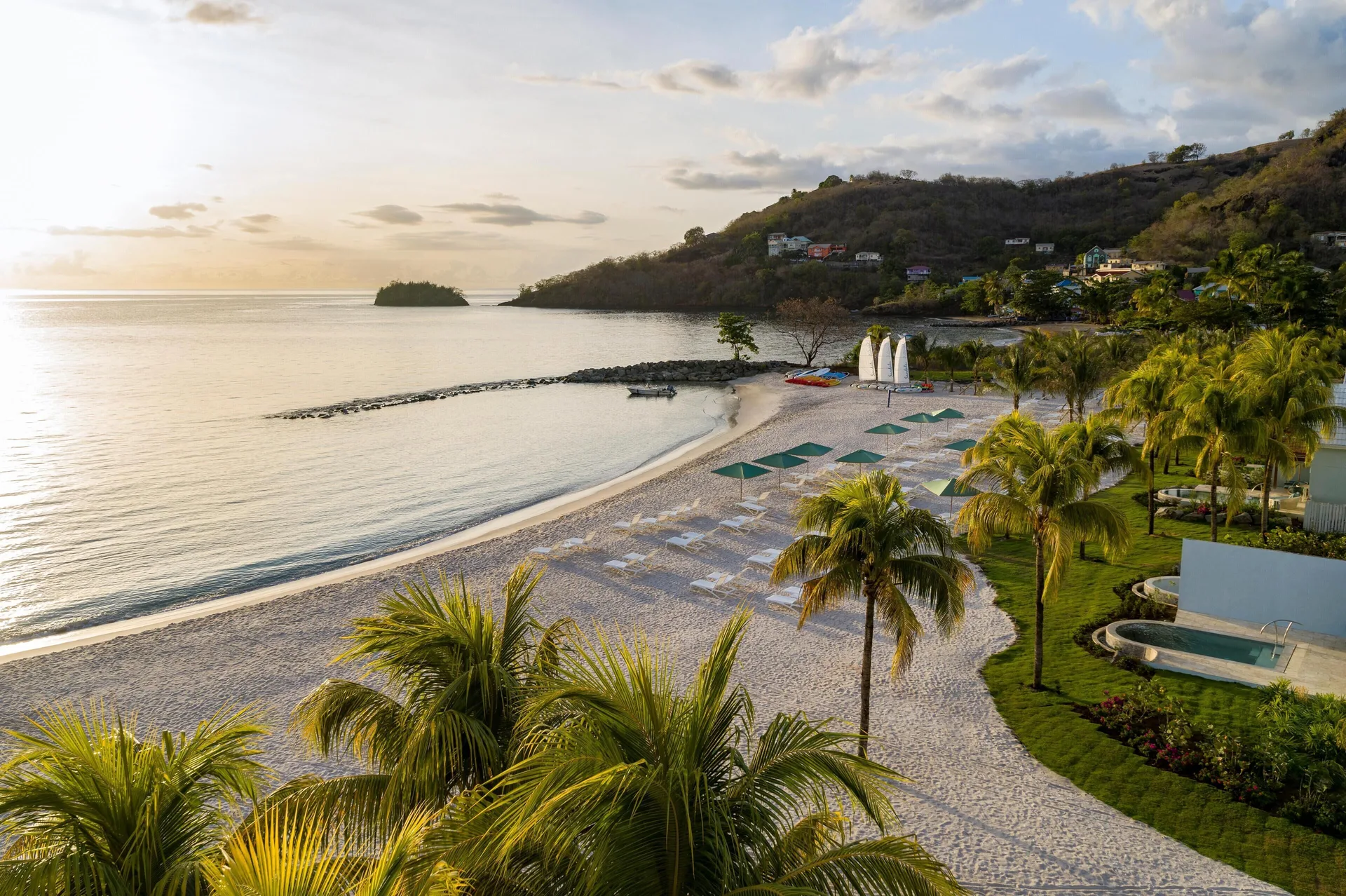 Sunlit beach with palms, loungers, and calm water at Sandals St. Vincent and the Grenadines.
