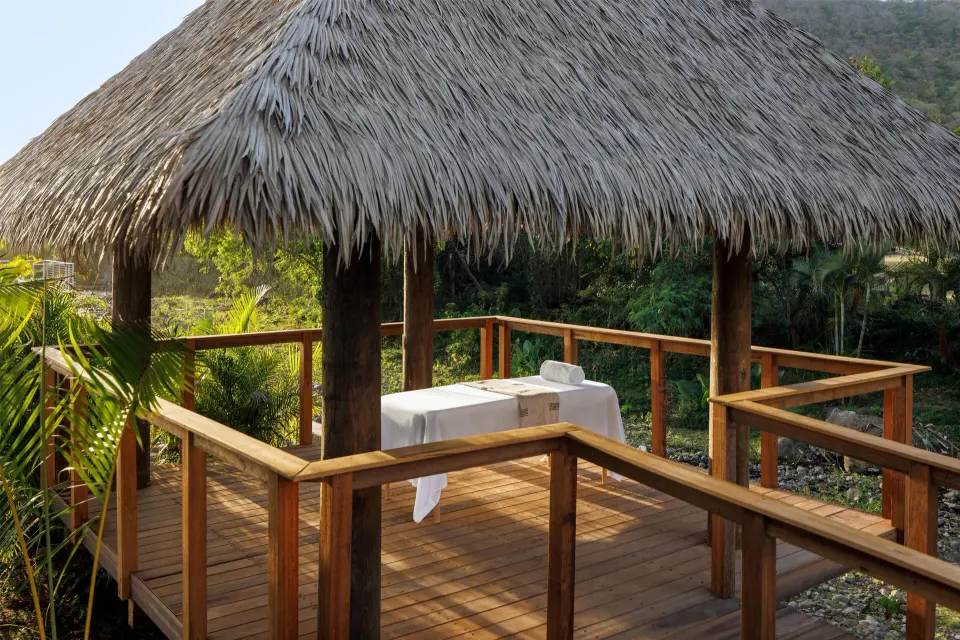 Thatched outdoor spa deck with a massage table at Sandals St. Vincent and the Grenadines.