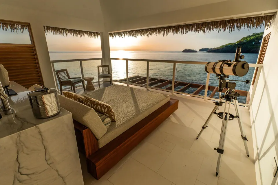 Overwater villa balcony with daybed and telescope at Sandals St. Vincent and the Grenadines.