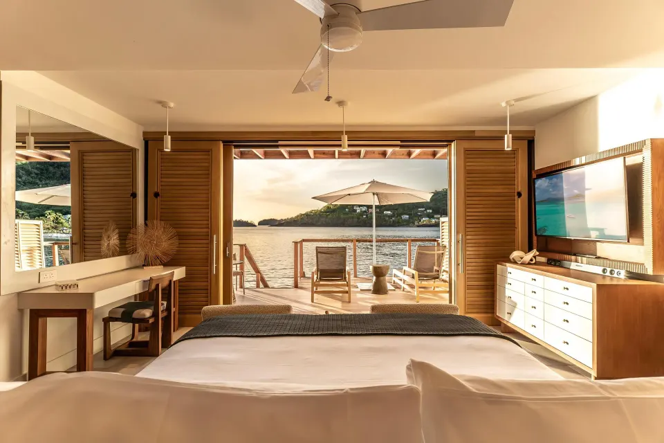 Vincy Overwater Two-Story Villa king bed facing the deck at Sandals St. Vincent and the Grenadines.