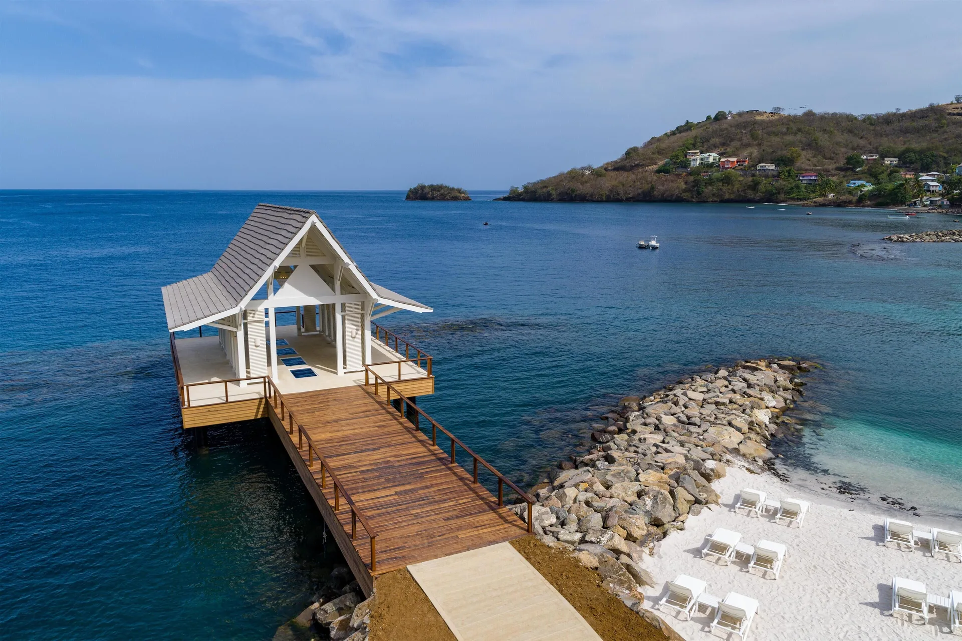 Overwater chapel, wooden pier, rocky breakwater and beach at Sandals St. Vincent and the Grenadines.