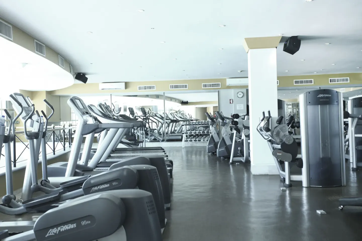 Rows of treadmills, cardio machines, and mirrors fill the fitness center at Sandos Cancún.