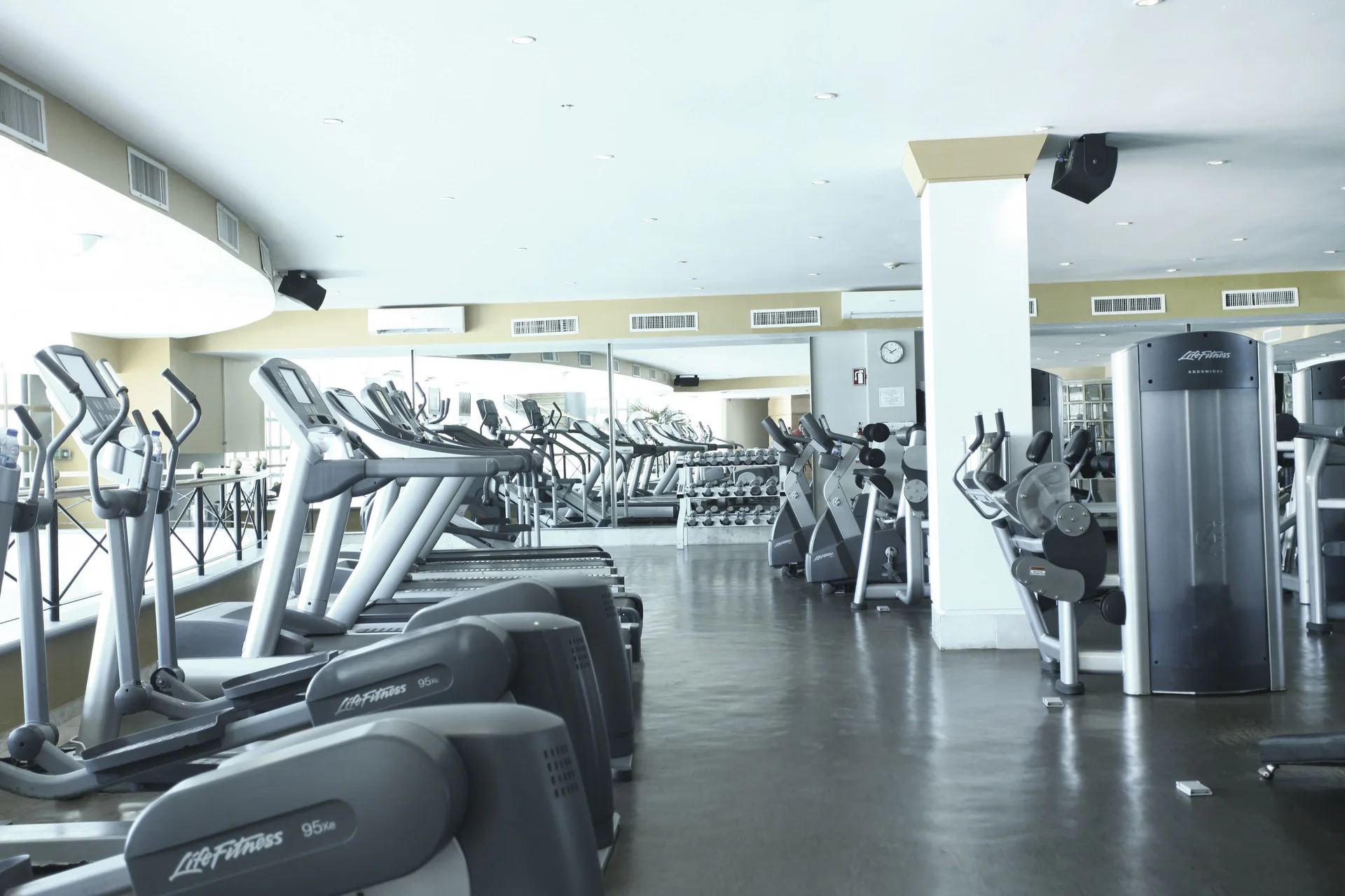 Rows of treadmills, cardio machines, and mirrors fill the fitness center at Sandos Cancún.