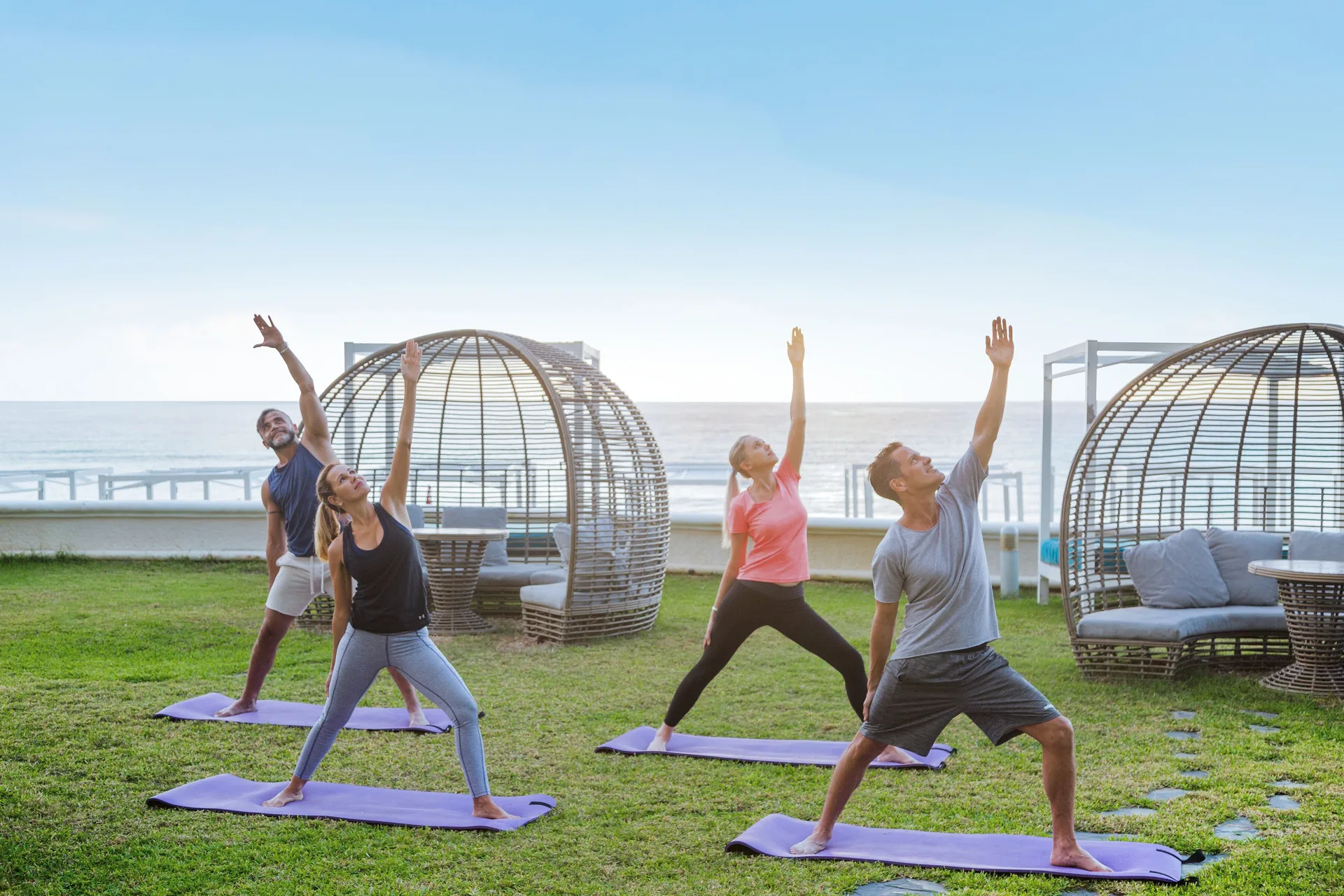 Guests practice yoga on a lawn facing the ocean at Sandos Cancún.
