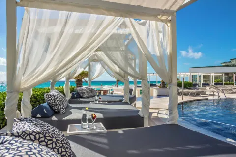 White curtained cabanas and loungers beside the pool at Sandos Cancún.
