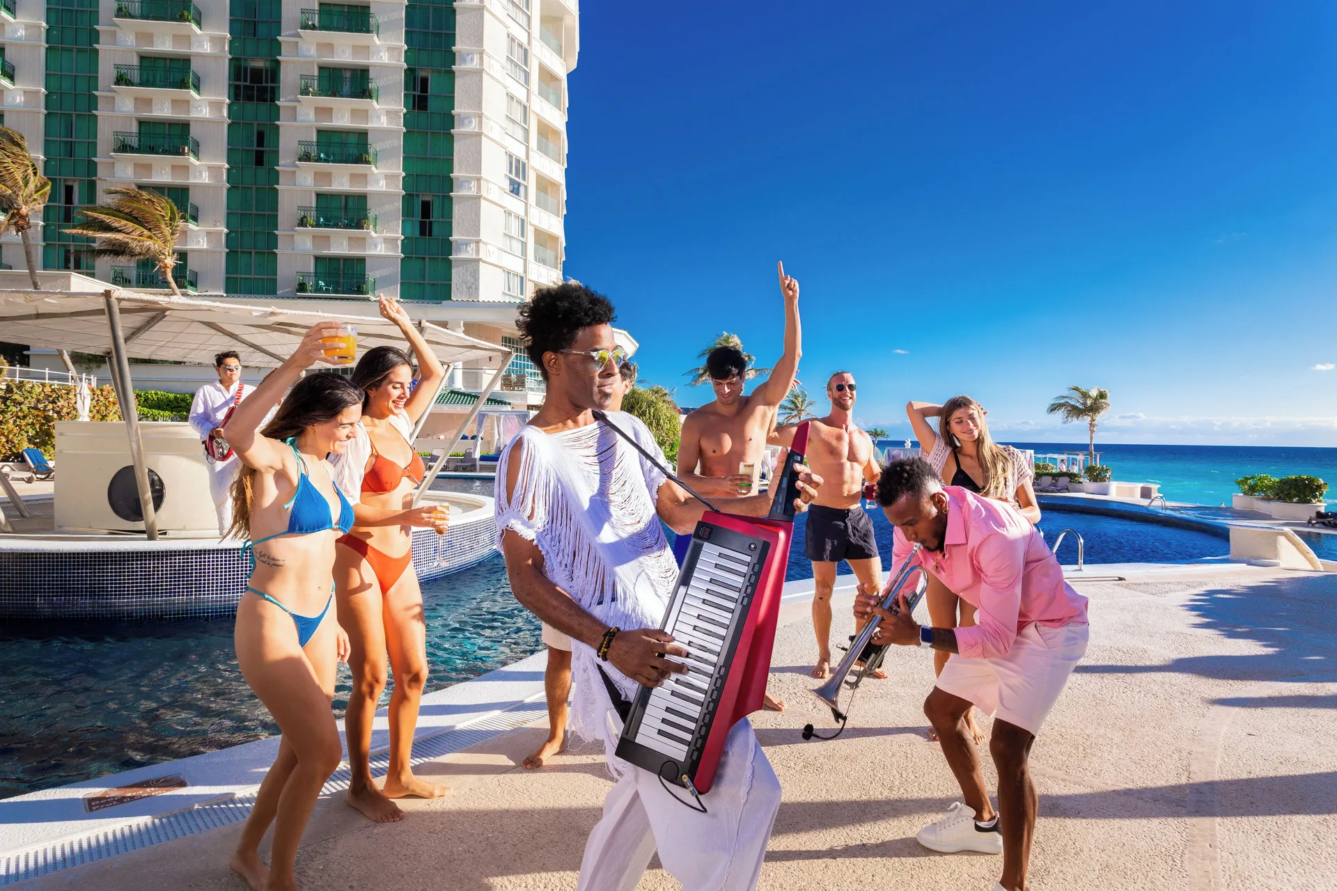Poolside musicians and dancing guests beside the ocean at Sandos Cancún.