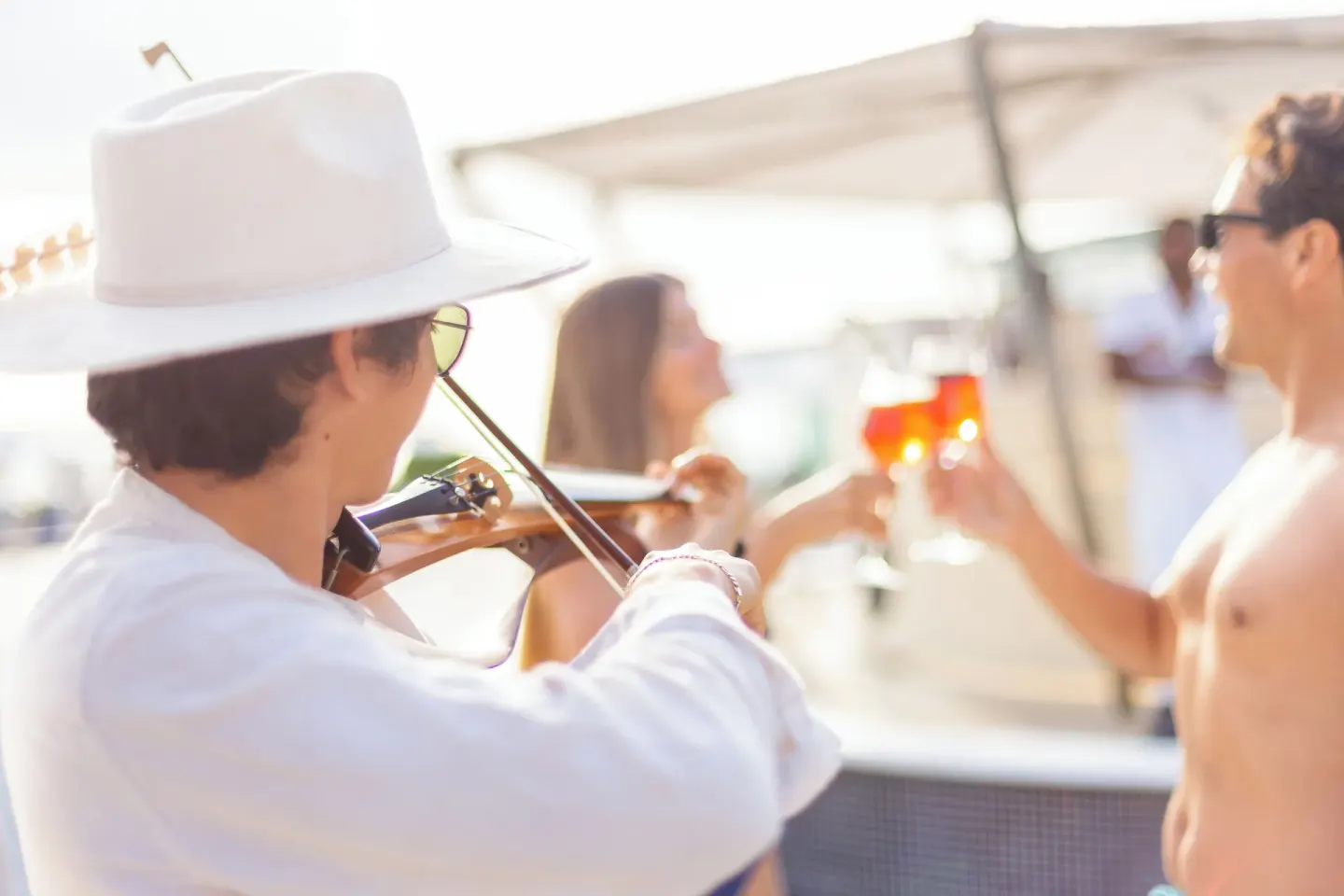 Violinist performing near guests with drinks by the pool at Sandos Cancún.