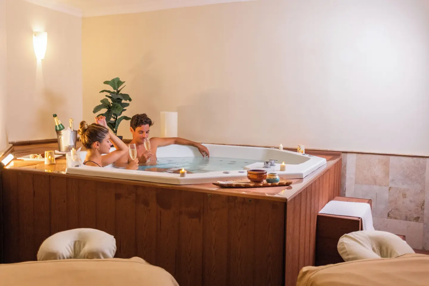 Couple enjoys a private indoor hot tub beside massage tables at Sandos Cancún.