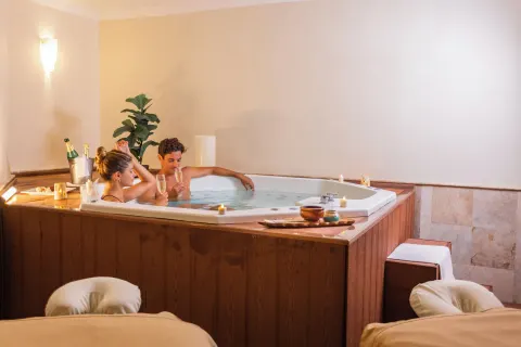 Couple enjoys a private indoor hot tub beside massage tables at Sandos Cancún.
