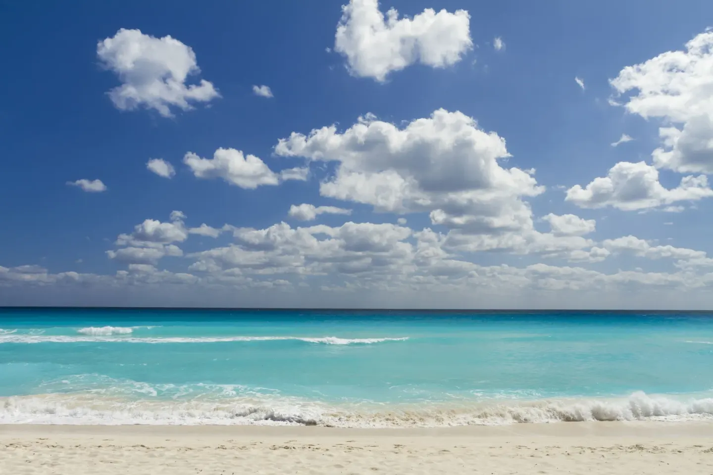 Turquoise ocean waves and white sand beach at Sandos Cancún.