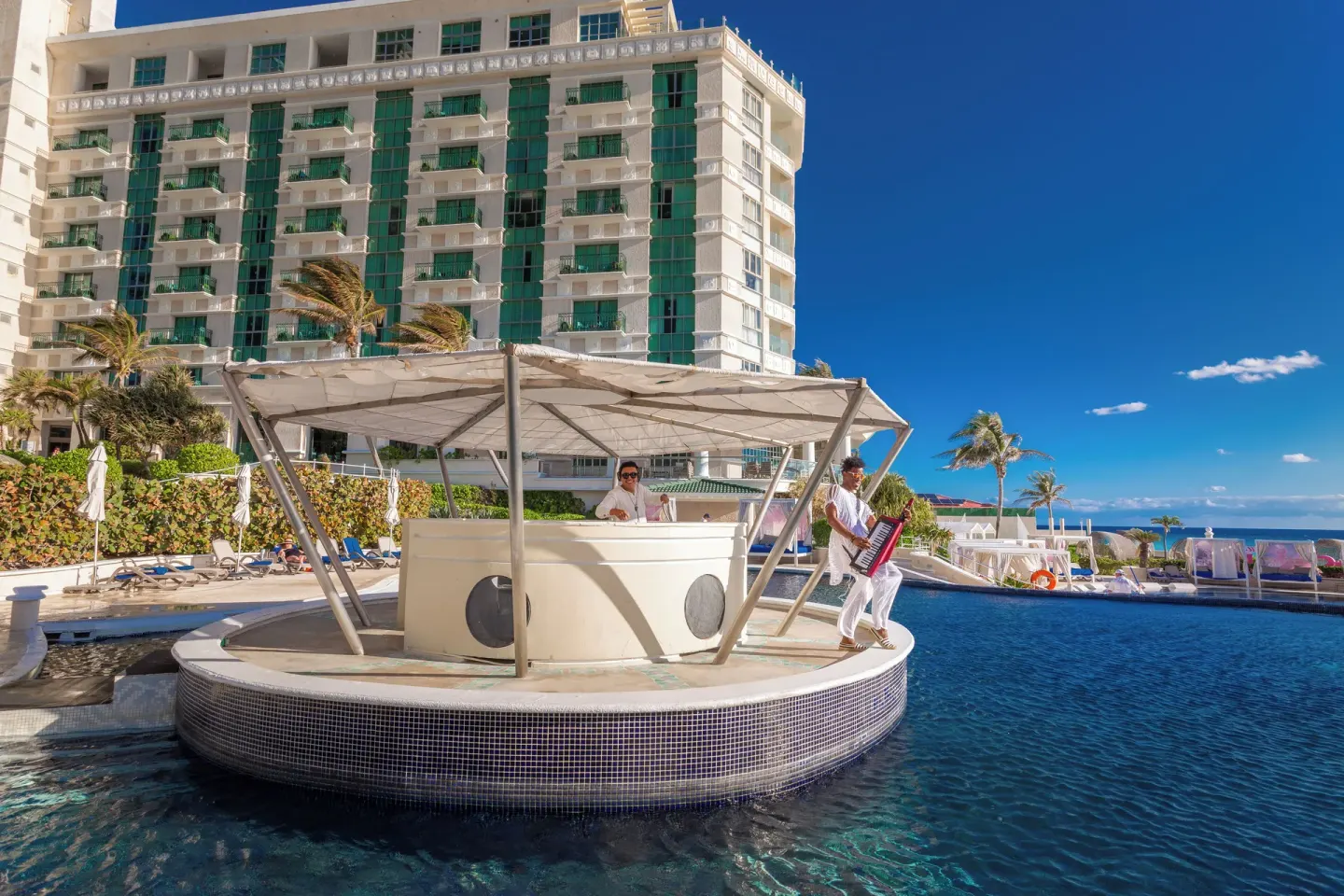 Pool bar with musicians and the hotel tower behind it at Sandos Cancún.