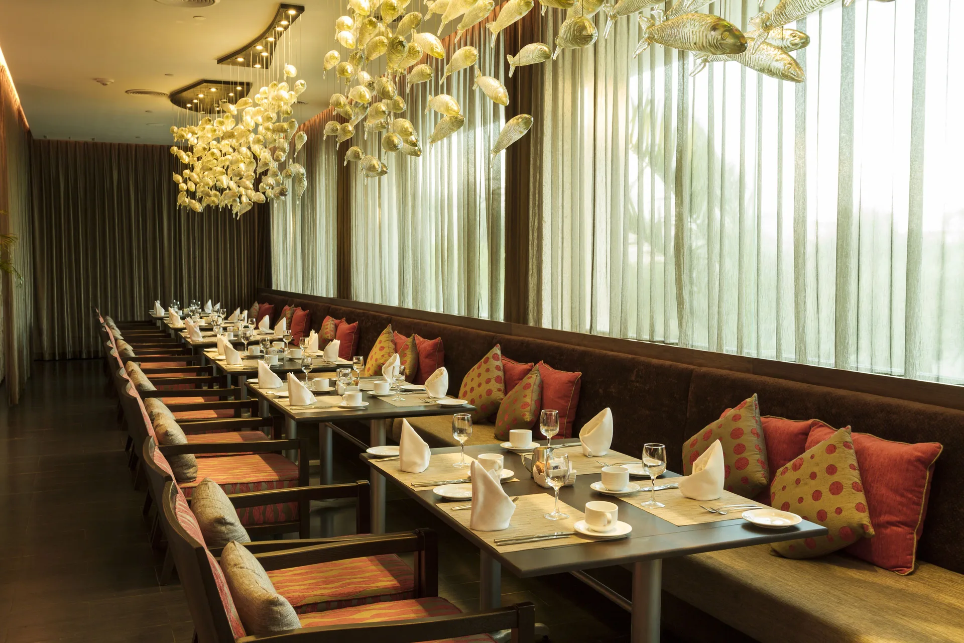 Dining room with set tables and hanging fish decor at Sandos Cancún.