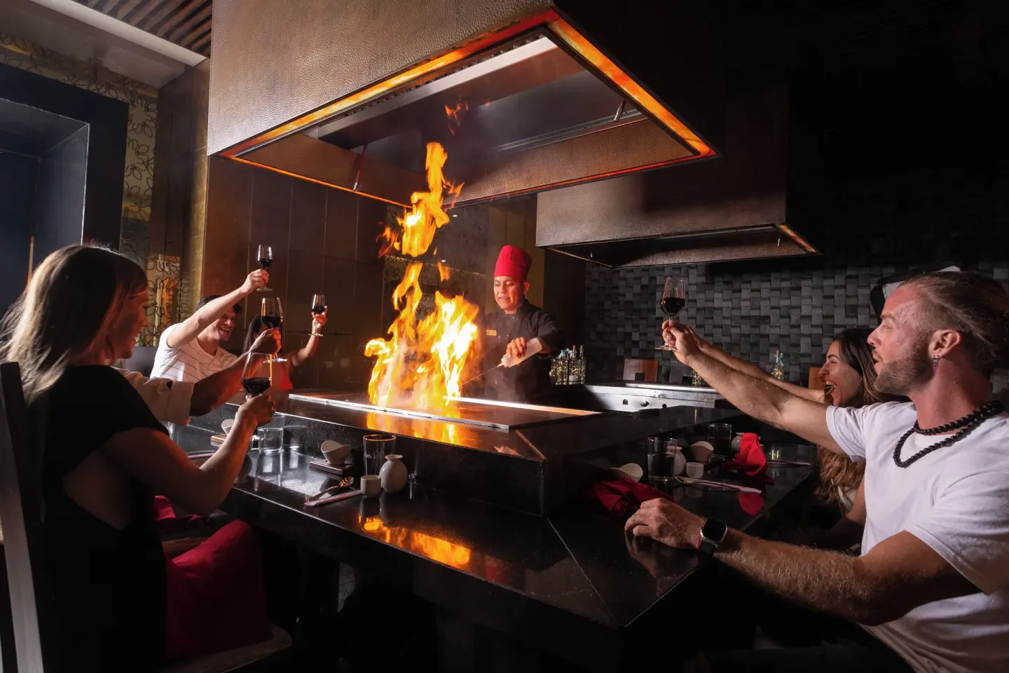 Teppanyaki chef cooking with flames for guests at Sandos Cancún.