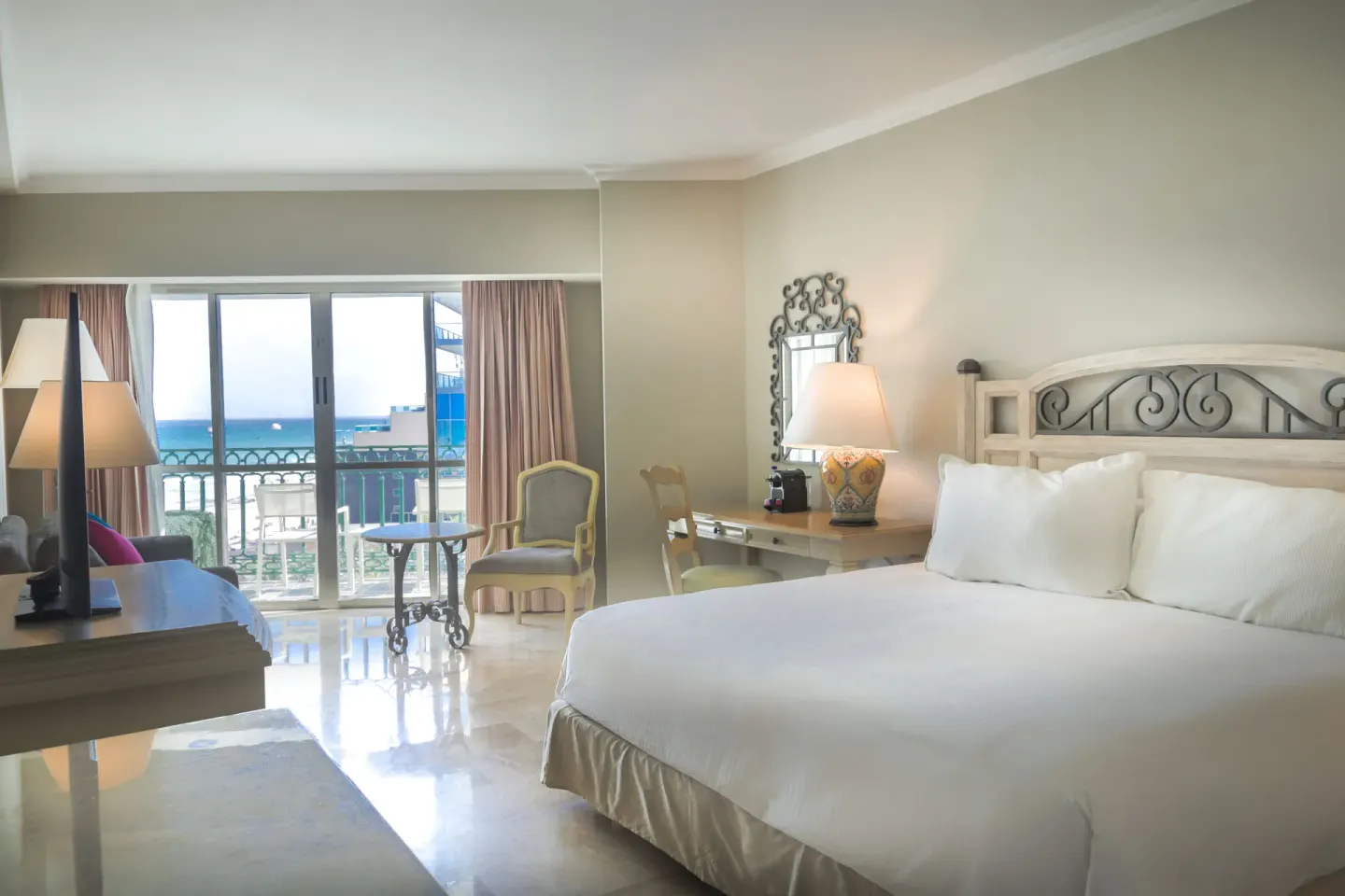 Balcony Deluxe Room king bed and ocean-facing balcony at Sandos Cancún.