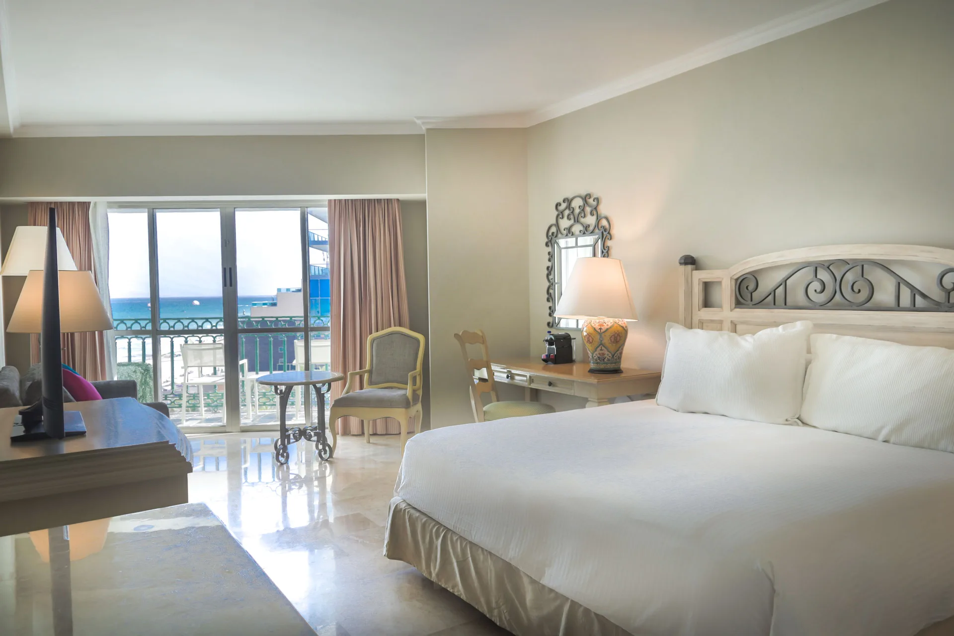 Balcony Deluxe Room king bed and ocean-facing balcony at Sandos Cancún.