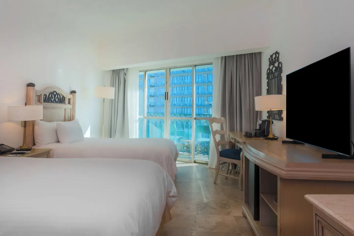 Balcony Deluxe Room with two beds, TV, desk, and balcony at Sandos Cancún.