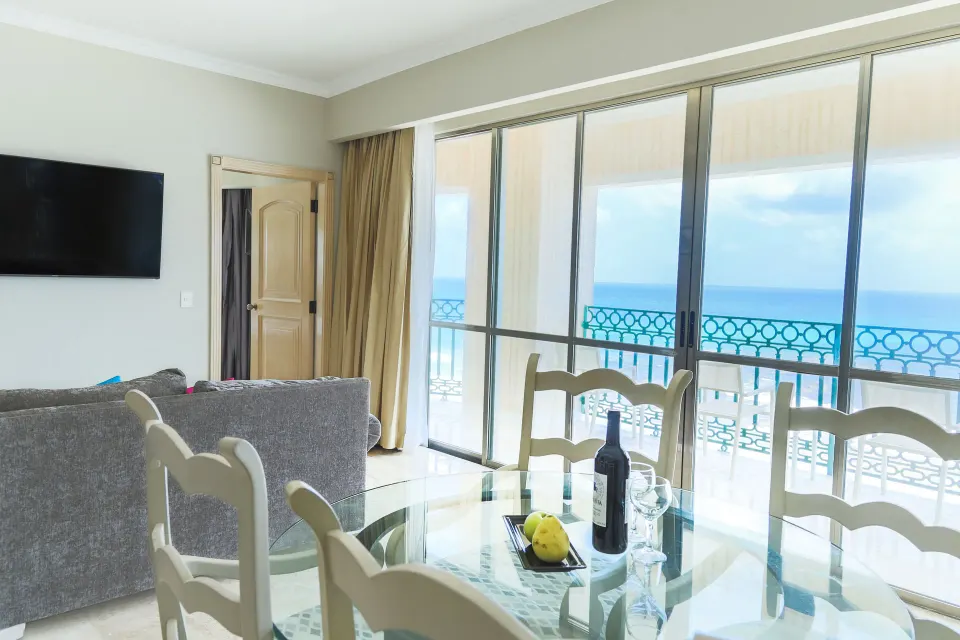 Caribe Suite living and dining area with balcony ocean view at Sandos Cancún.