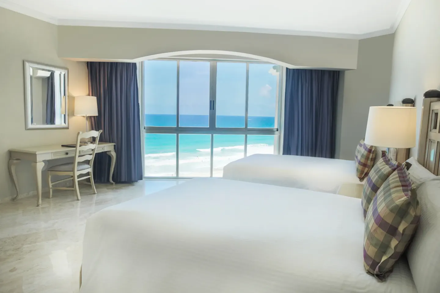 Caribe Suite two-bed bedroom with ocean view window at Sandos Cancún.