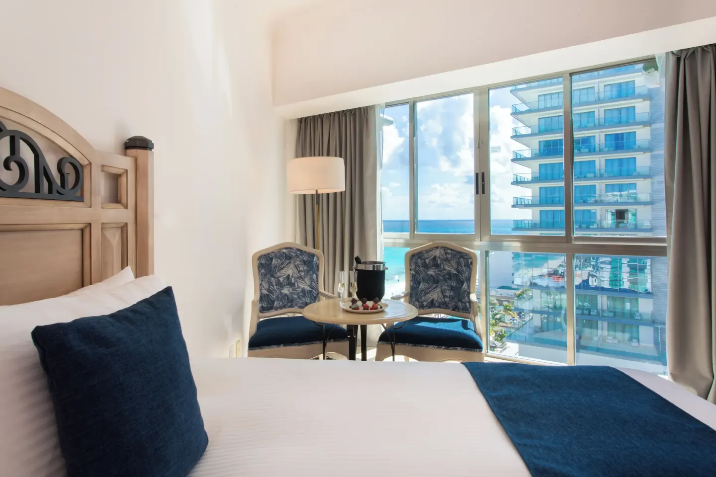Deluxe Room king bed and ocean-facing sitting area at Sandos Cancún.