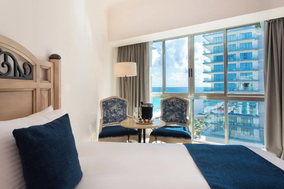 Deluxe Room king bed and ocean-facing sitting area at Sandos Cancún.
