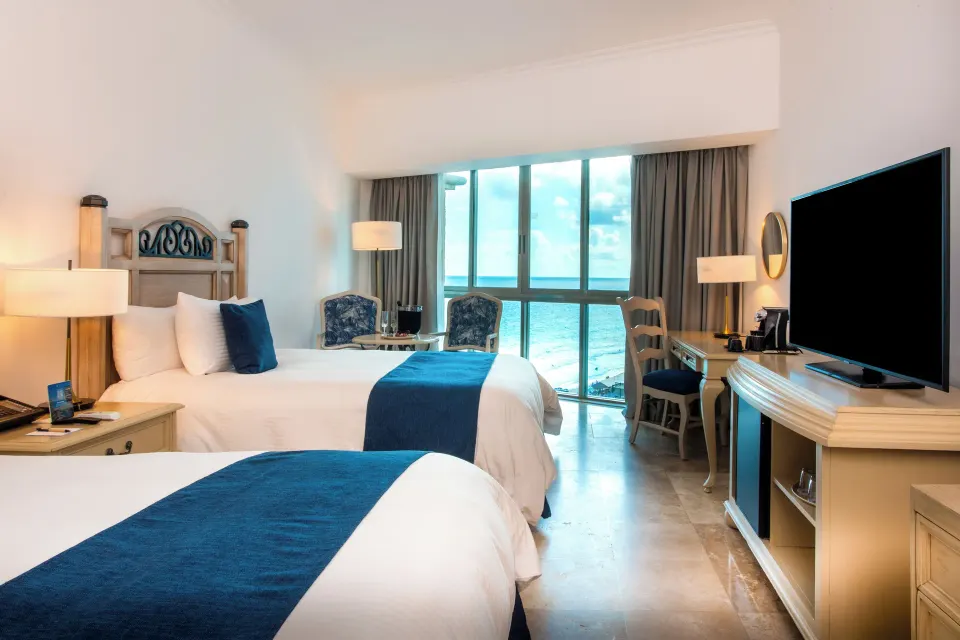 Deluxe Room with two beds, TV, desk, and ocean view at Sandos Cancún.