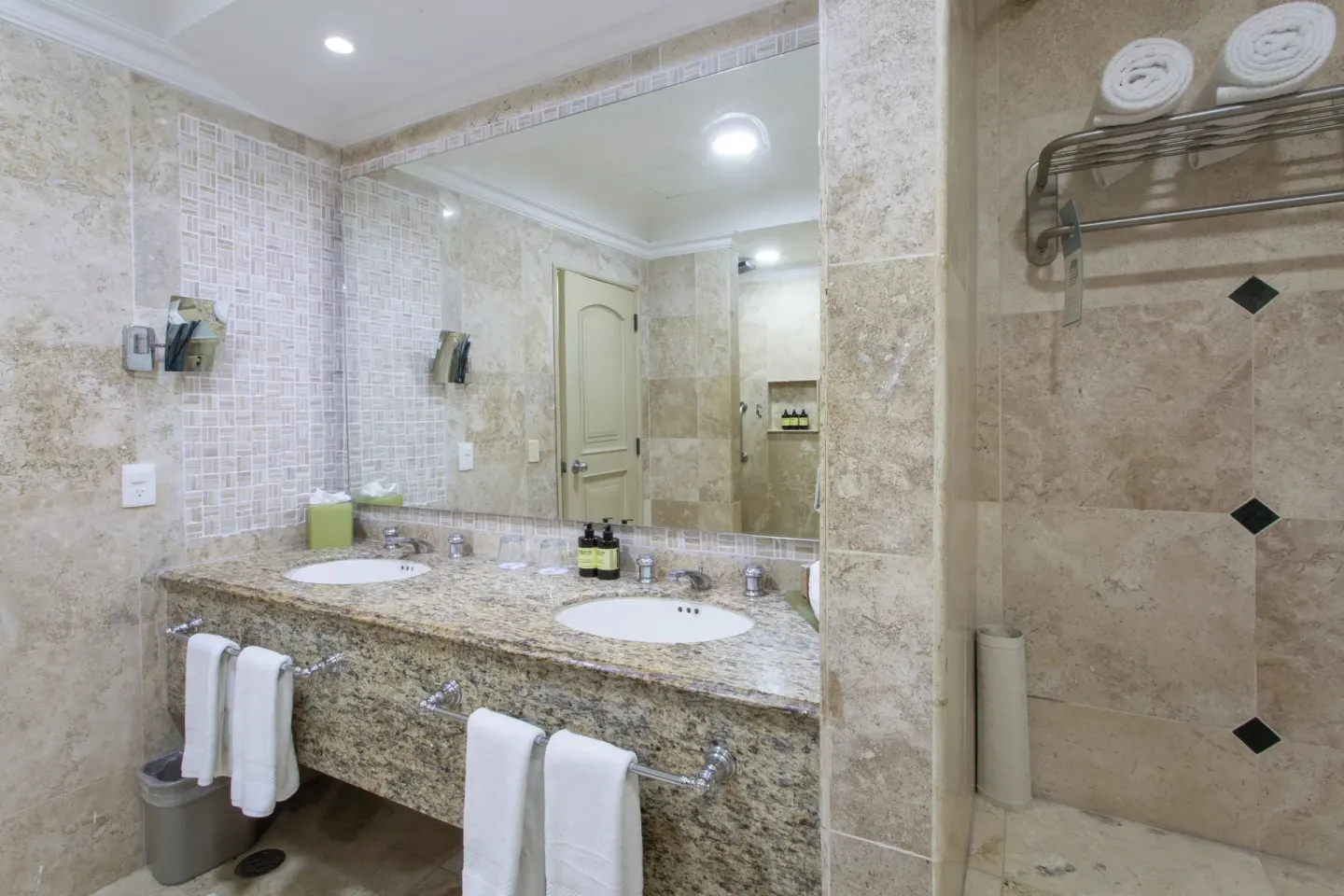 Laguna Suite bathroom with double sinks, large mirror, towels, and tiled shower at Sandos Cancún.