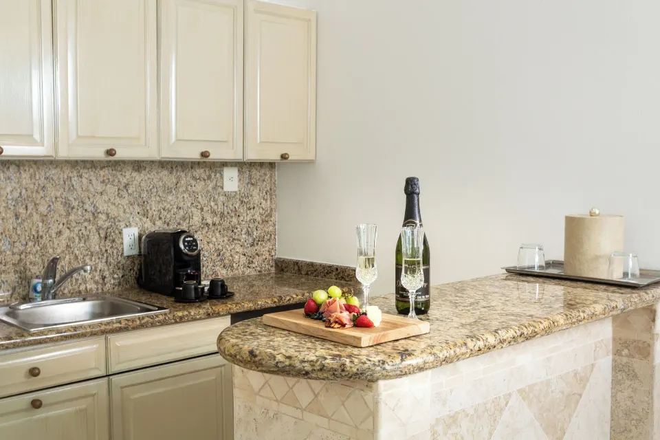 Laguna Suite kitchenette with granite counter, sink, coffee maker, glasses, and tray at Sandos Cancún.