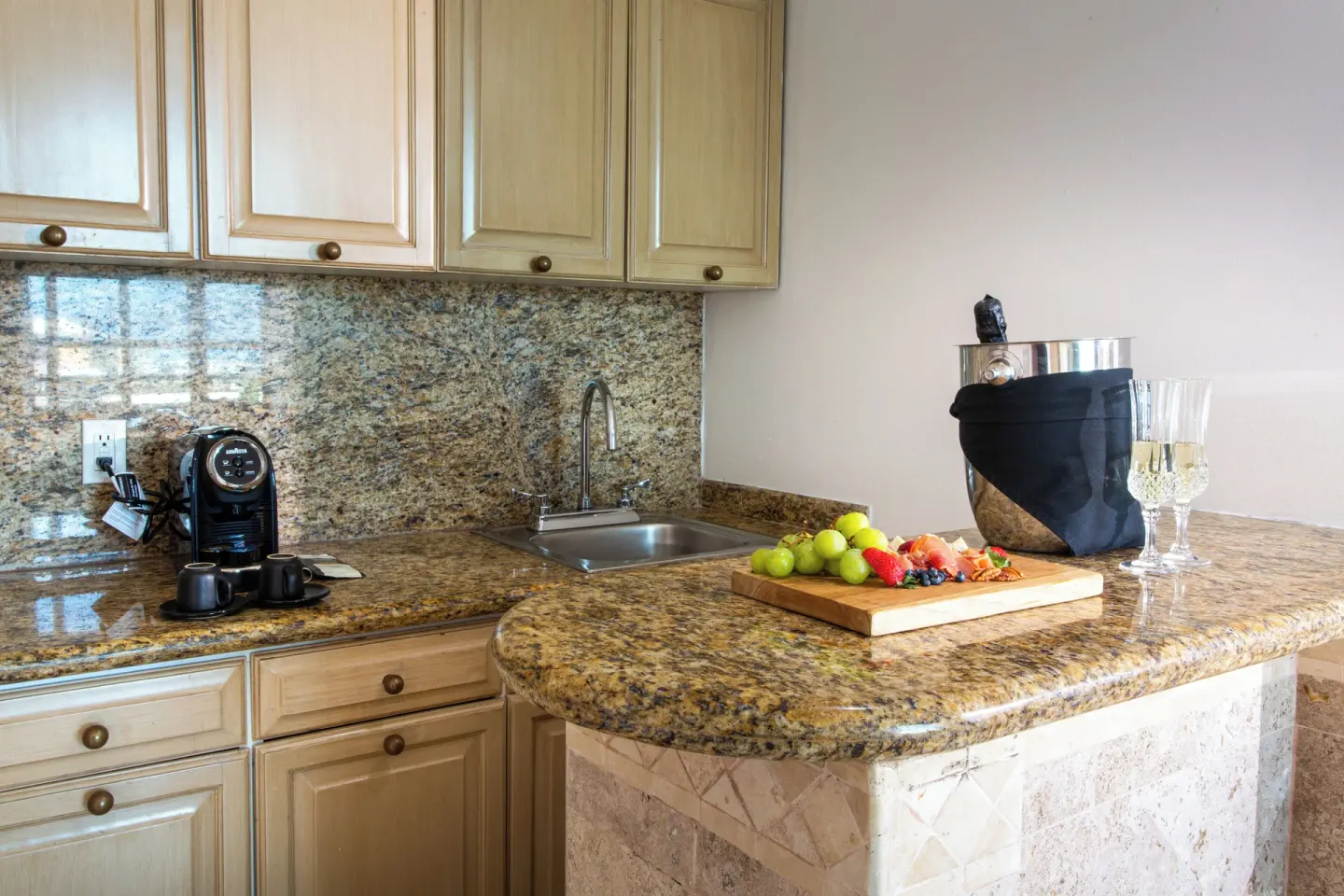 Sandos Cancún kitchenette with granite counter, sink, coffee maker, and chilled wine at Sandos Cancún.