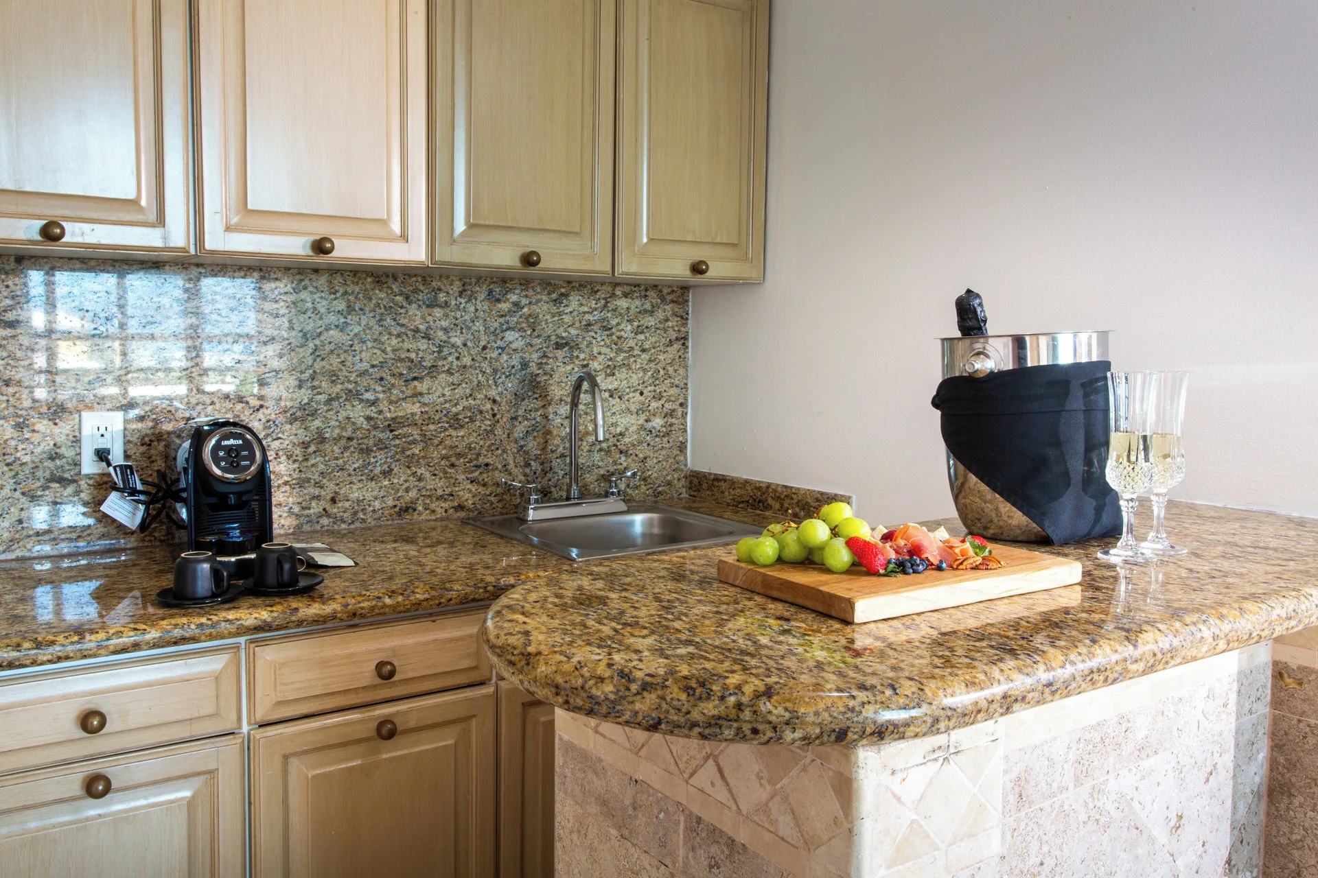 Sandos Cancún kitchenette with granite counter, sink, coffee maker, and chilled wine at Sandos Cancún.