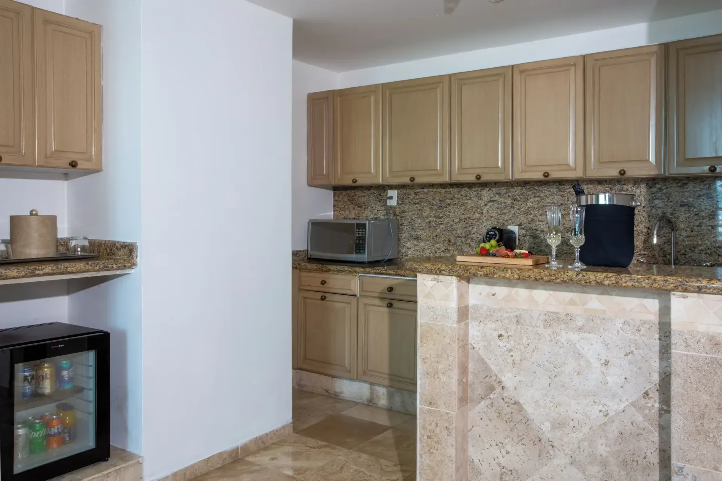 Sandos Cancún wet bar with cabinetry, microwave, mini fridge, and granite counter at Sandos Cancún.