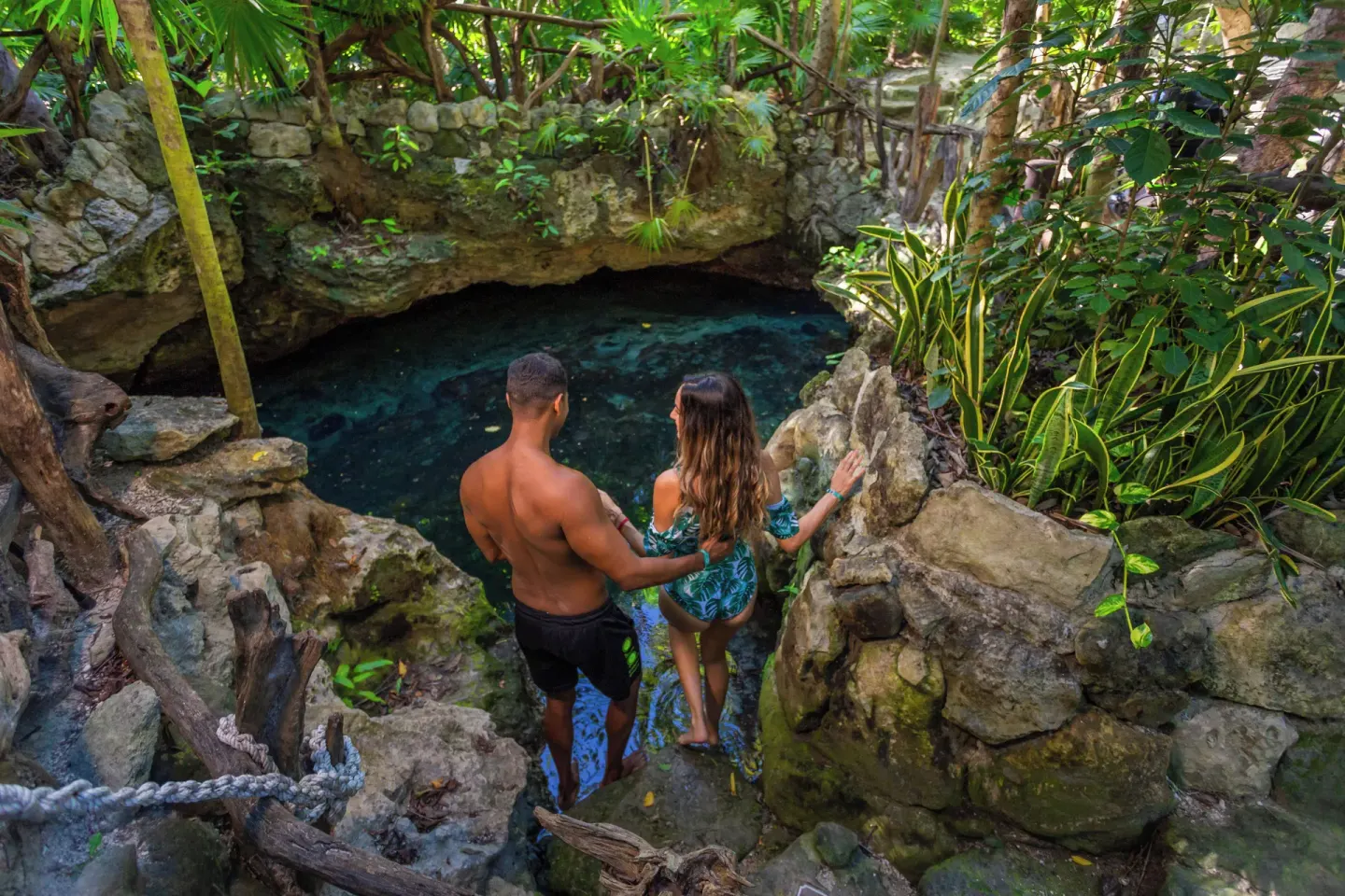 Couple walking down stone steps to a cenote at Sandos Caracol Nature Resort & Water Park.