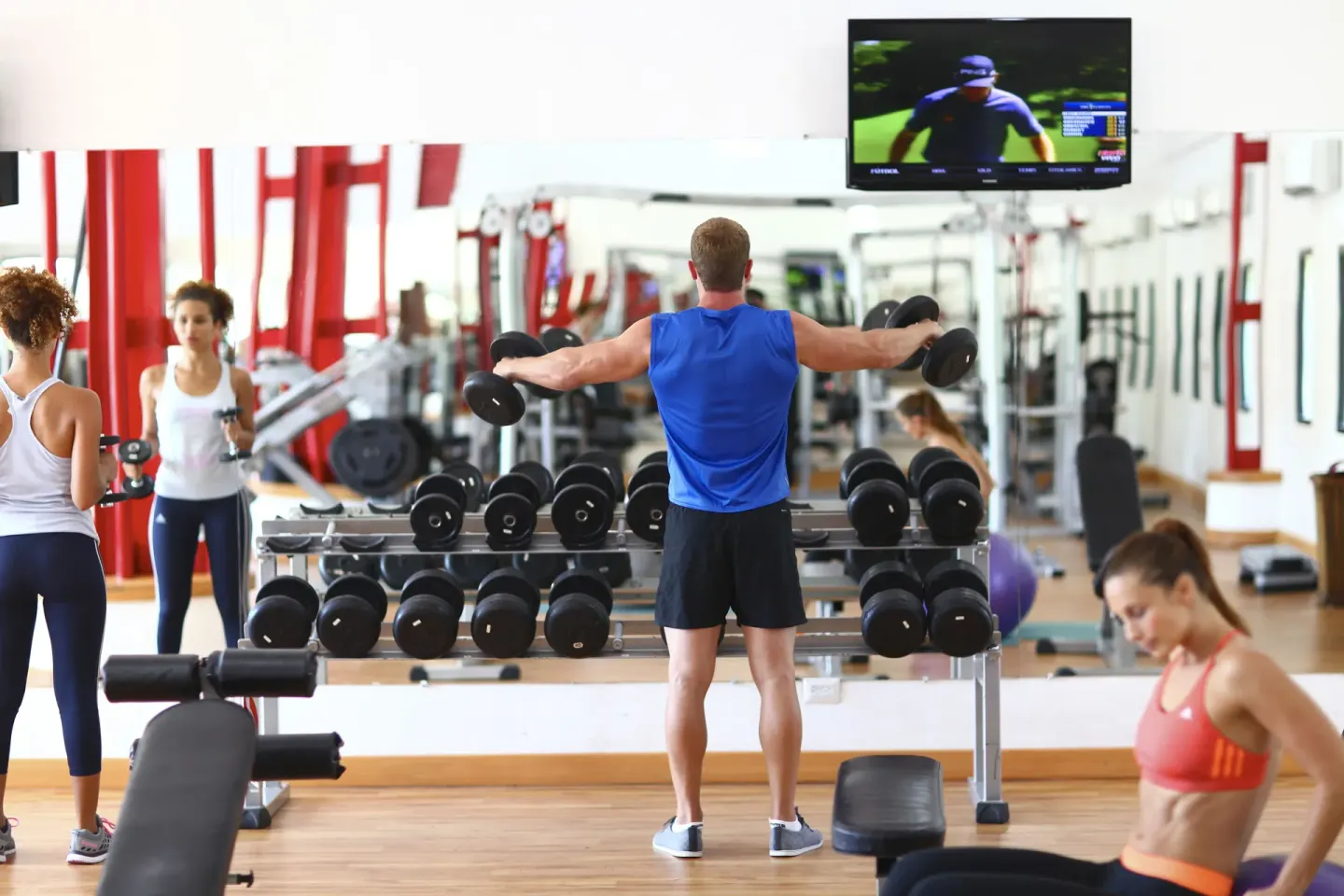 Guests lifting dumbbells in the fitness center at Sandos Caracol Nature Resort & Water Park.