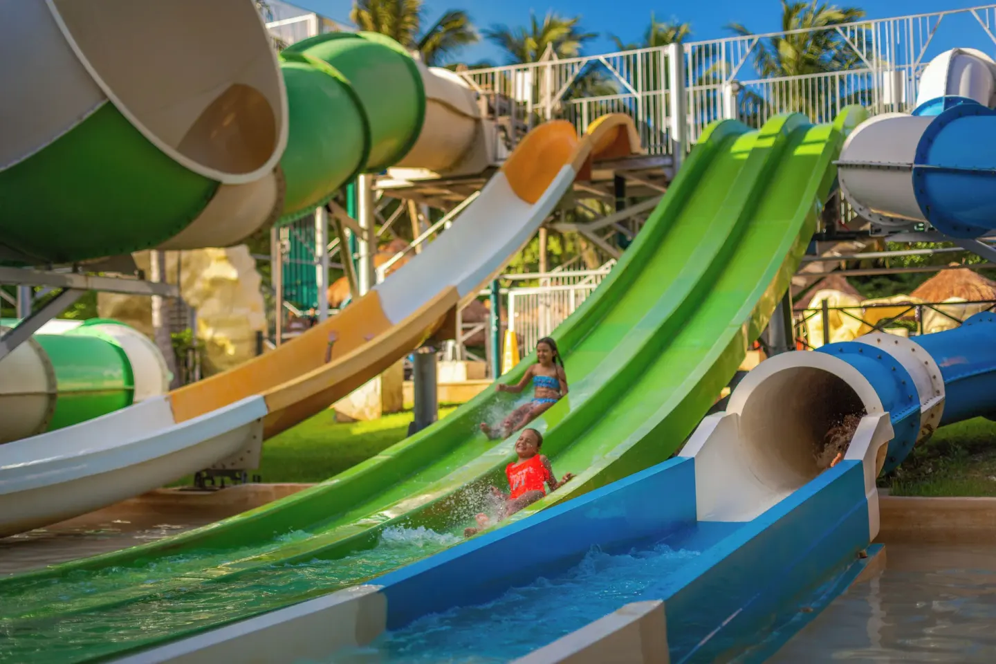 Children splash down green and blue slides at Sandos Caracol Nature Resort & Water Park.