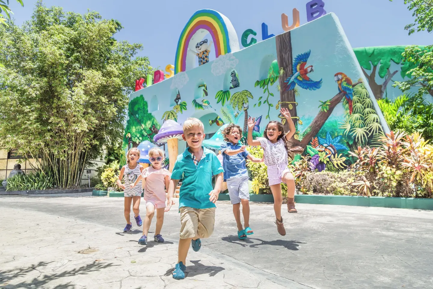Children running in front of the kids club mural at Sandos Caracol Nature Resort & Water Park.