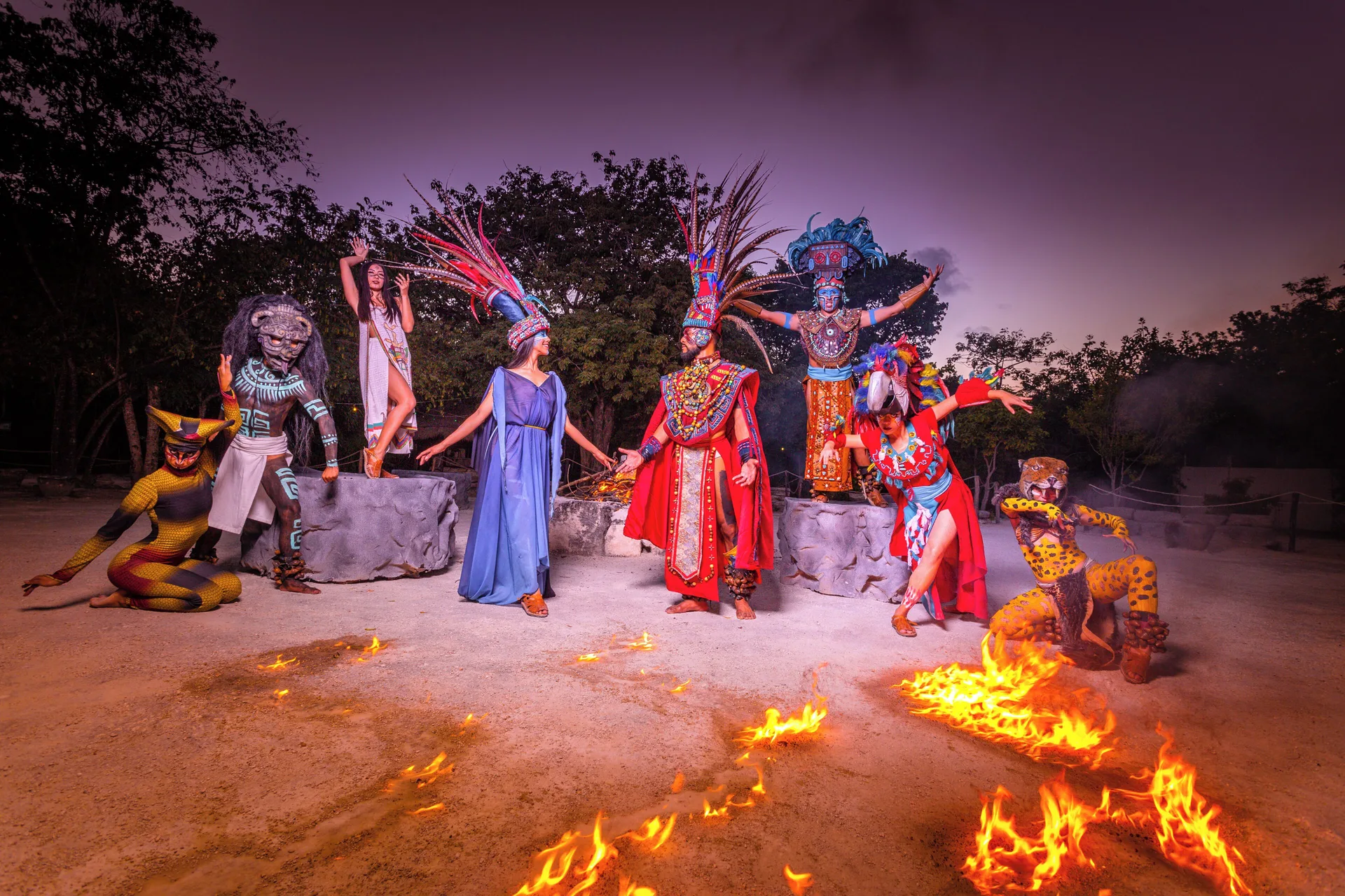 Costumed performers pose around flames at night at Sandos Caracol Nature Resort & Water Park.