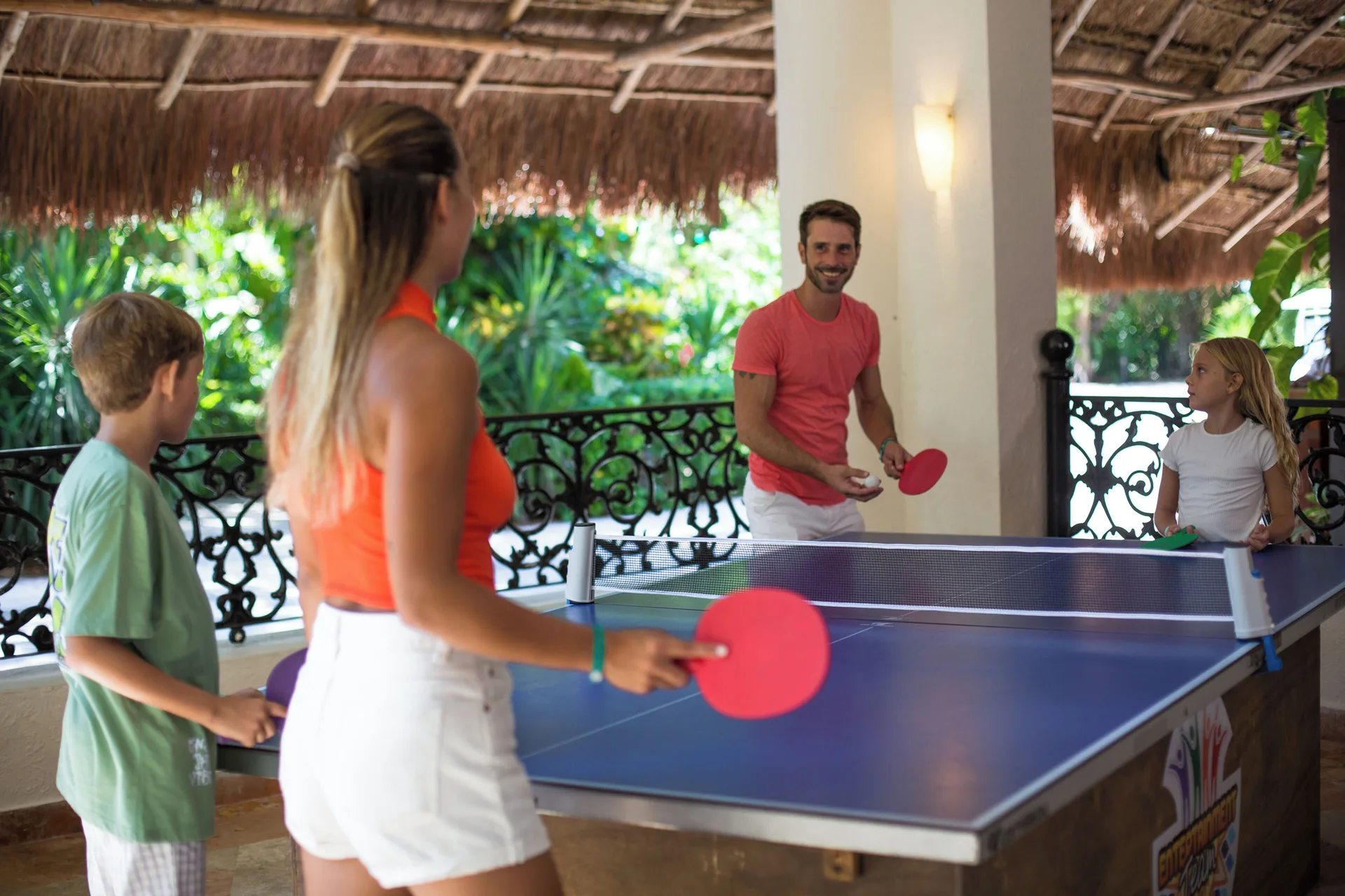 A family plays table tennis in a covered area at Sandos Caracol Nature Resort & Water Park.