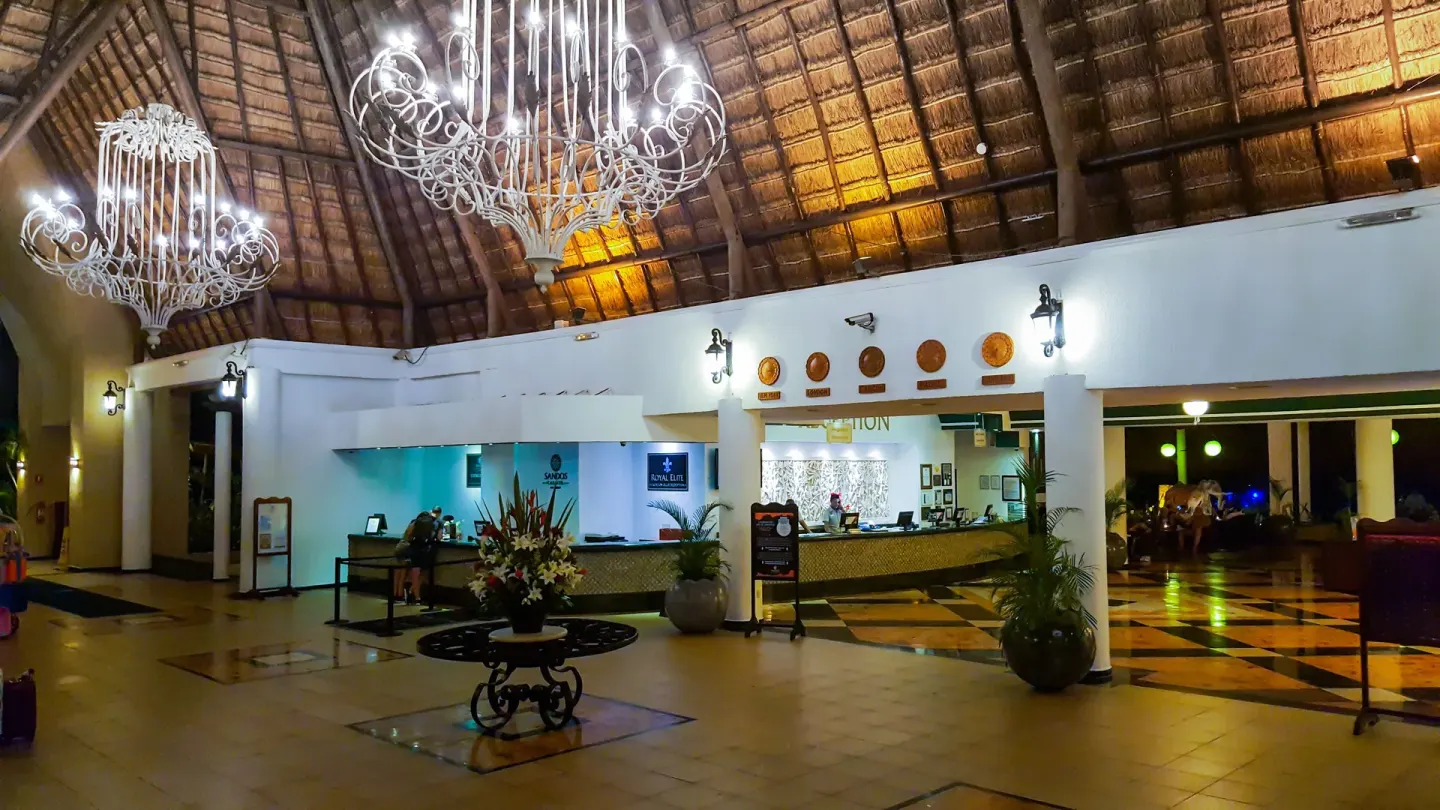 Thatched-roof lobby with reception desks at Sandos Caracol Nature Resort & Water Park.