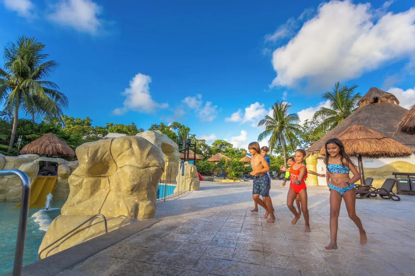Children run beside the water park pool at Sandos Caracol Nature Resort & Water Park.
