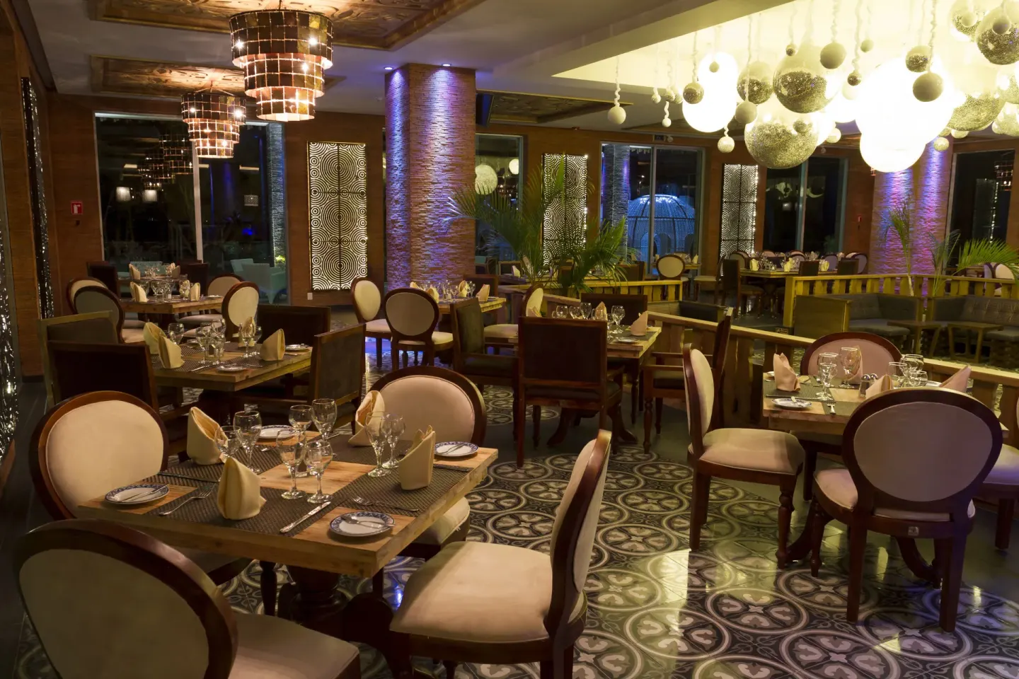 A warmly lit dining room with set tables at Sandos Caracol Nature Resort & Water Park.