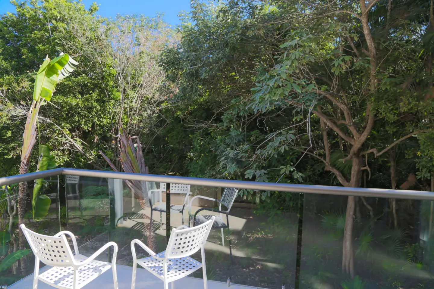 Eco Family Superior balcony with chairs and trees at Sandos Caracol Nature Resort & Water Park.