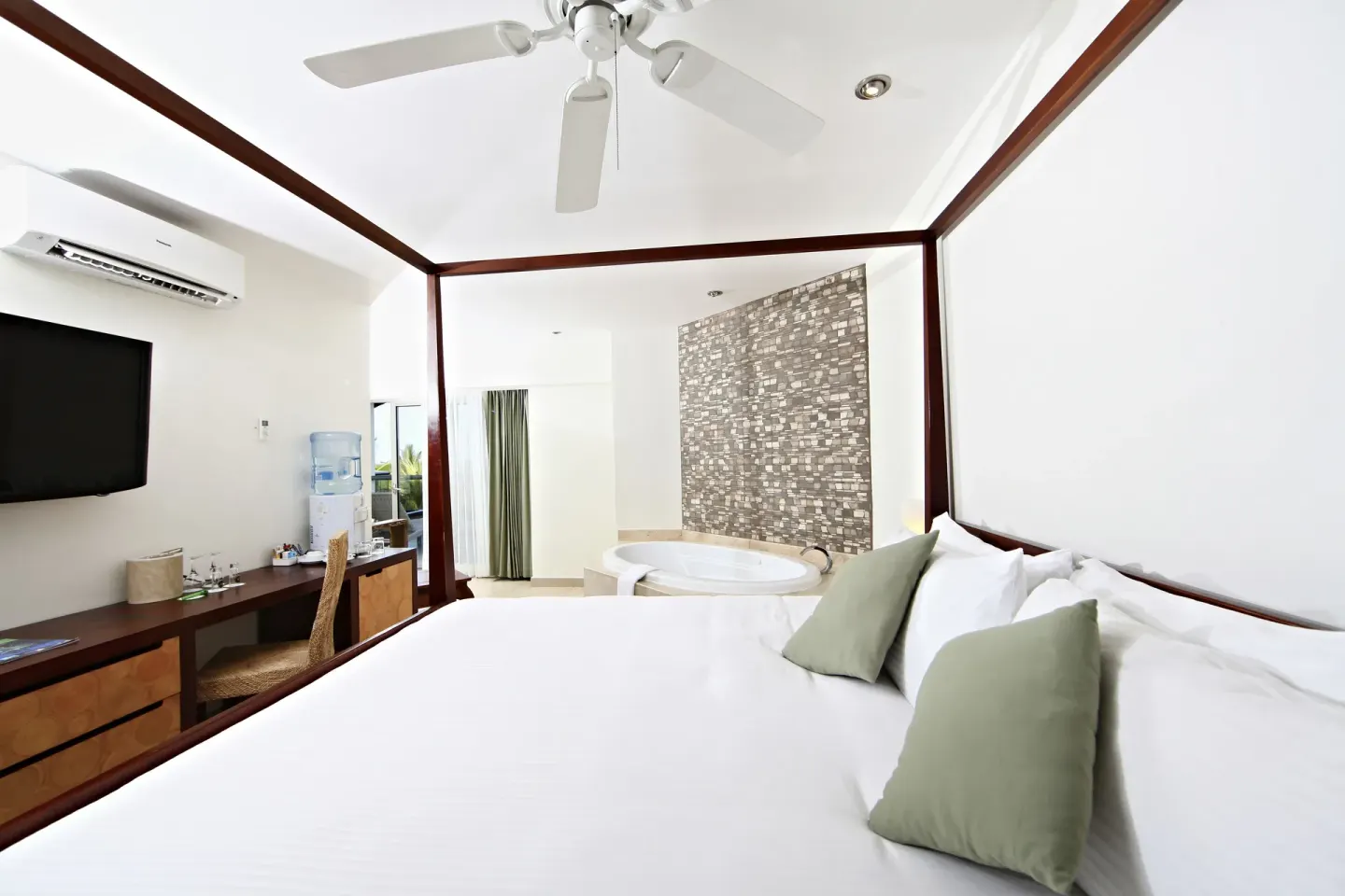 Pool View Penthouse king bed, tub, desk and TV at Sandos Caracol Nature Resort & Water Park.
