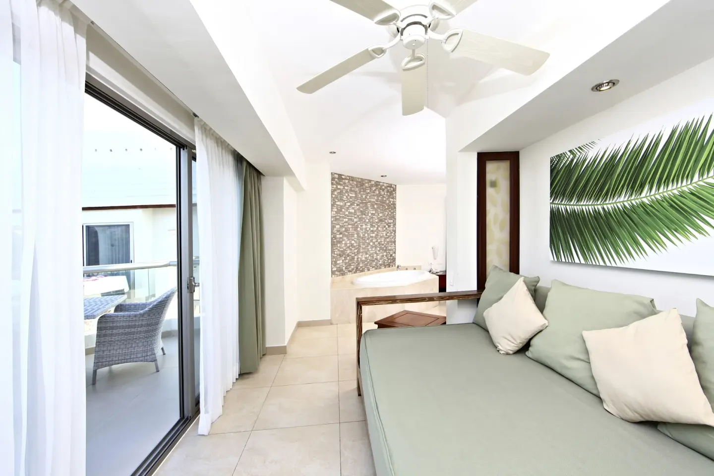 Pool View Penthouse lounge, balcony doors and round tub at Sandos Caracol Nature Resort & Water Park.