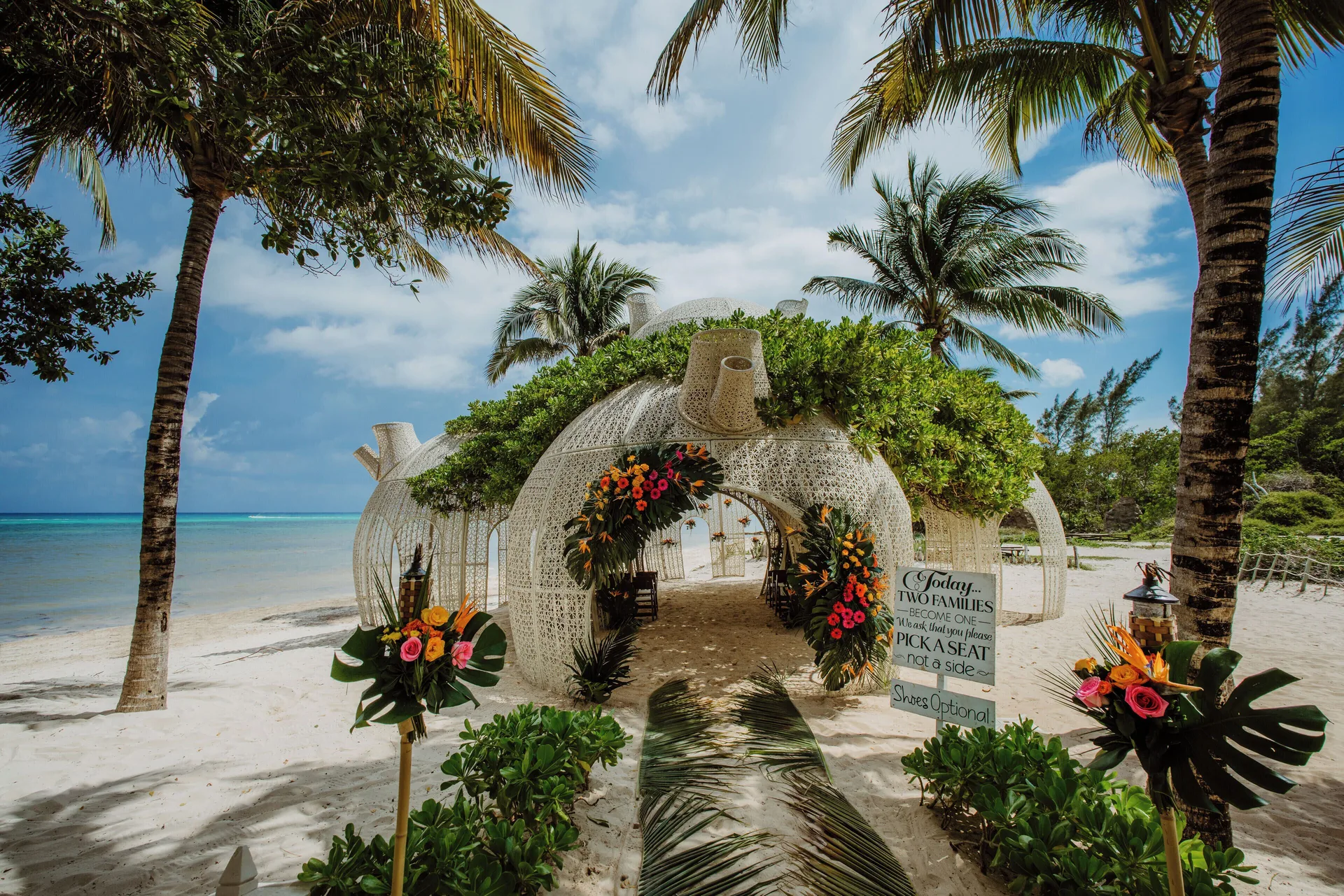Beach wedding setup with floral arches at Sandos Caracol Nature Resort & Water Park.