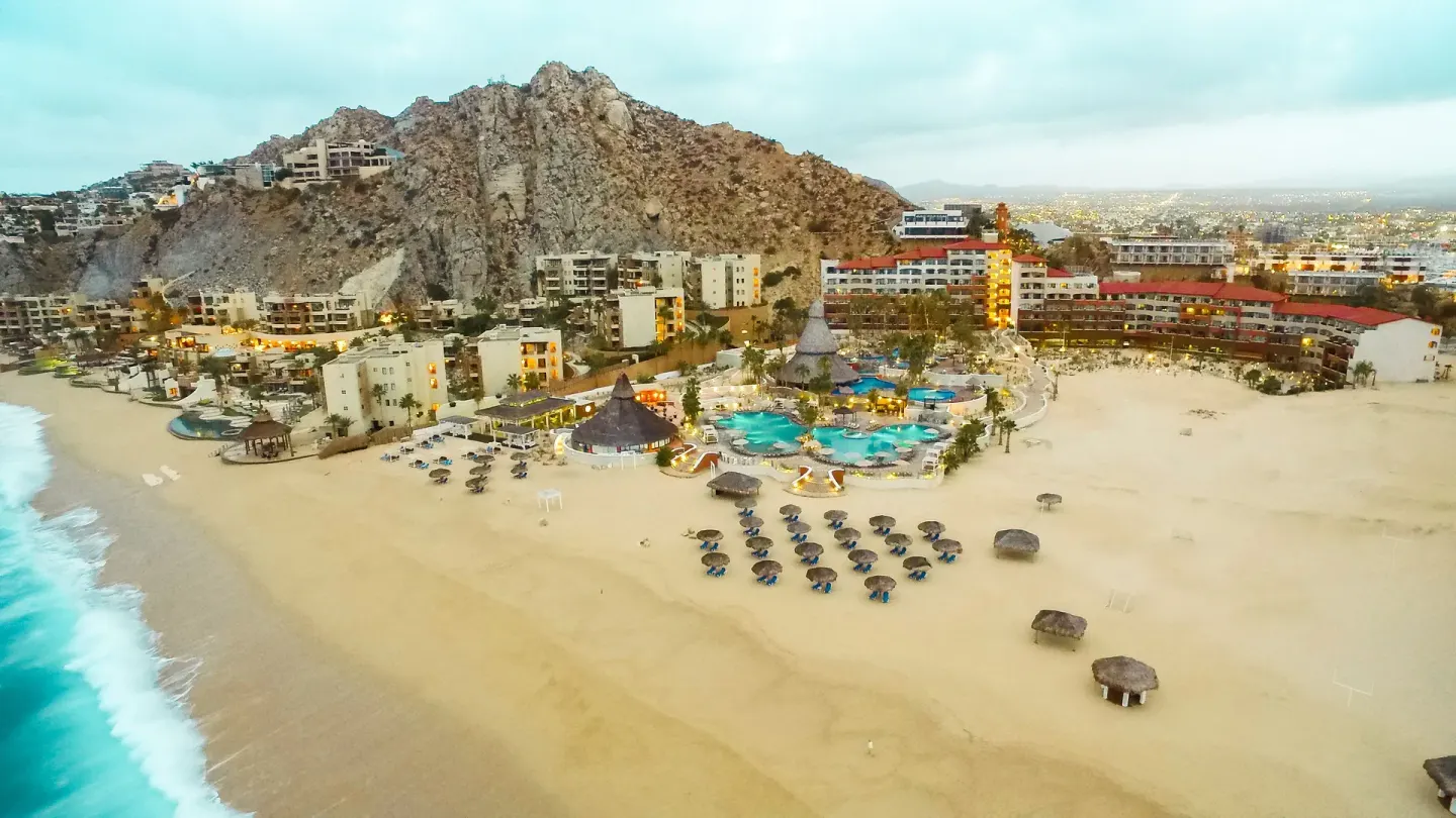 Aerial view of the beach, pools, and hillside buildings at Sandos Finisterra.