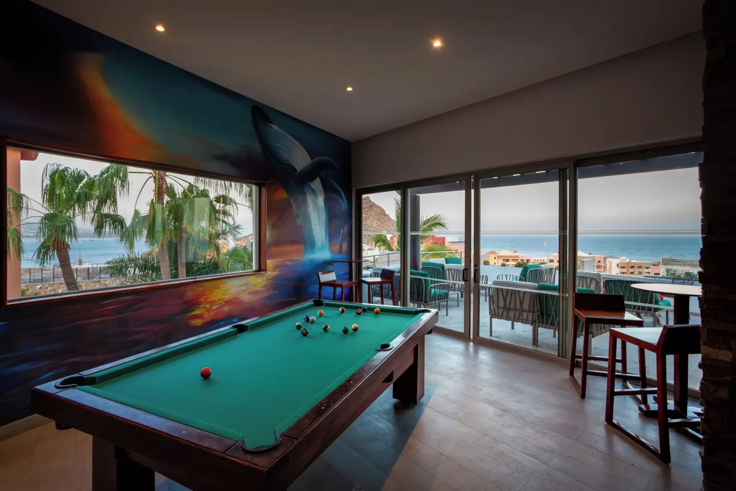 Billiards room with ocean-view balcony and whale mural at Sandos Finisterra.
