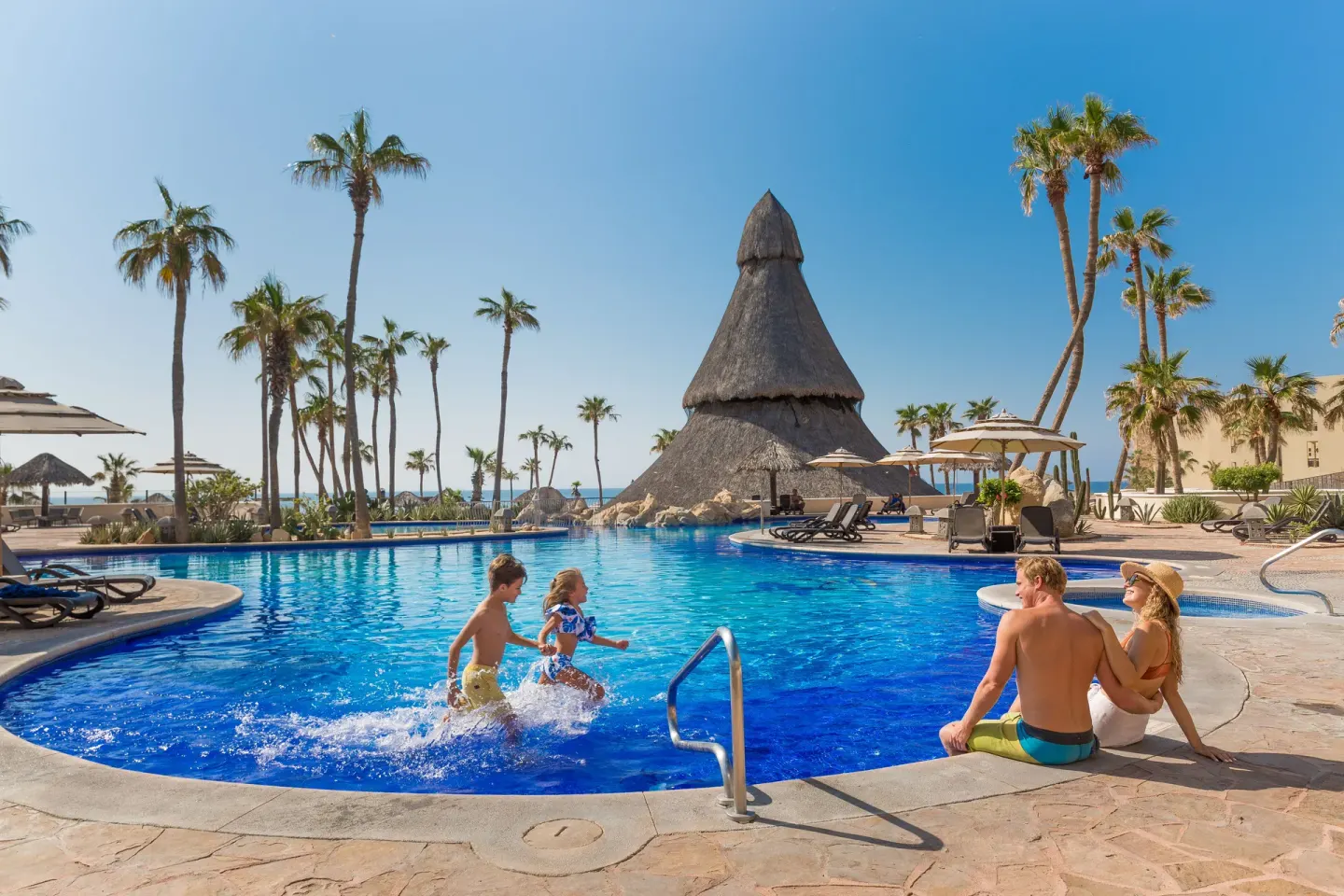 Families play by a bright blue pool with palms at Sandos Finisterra.
